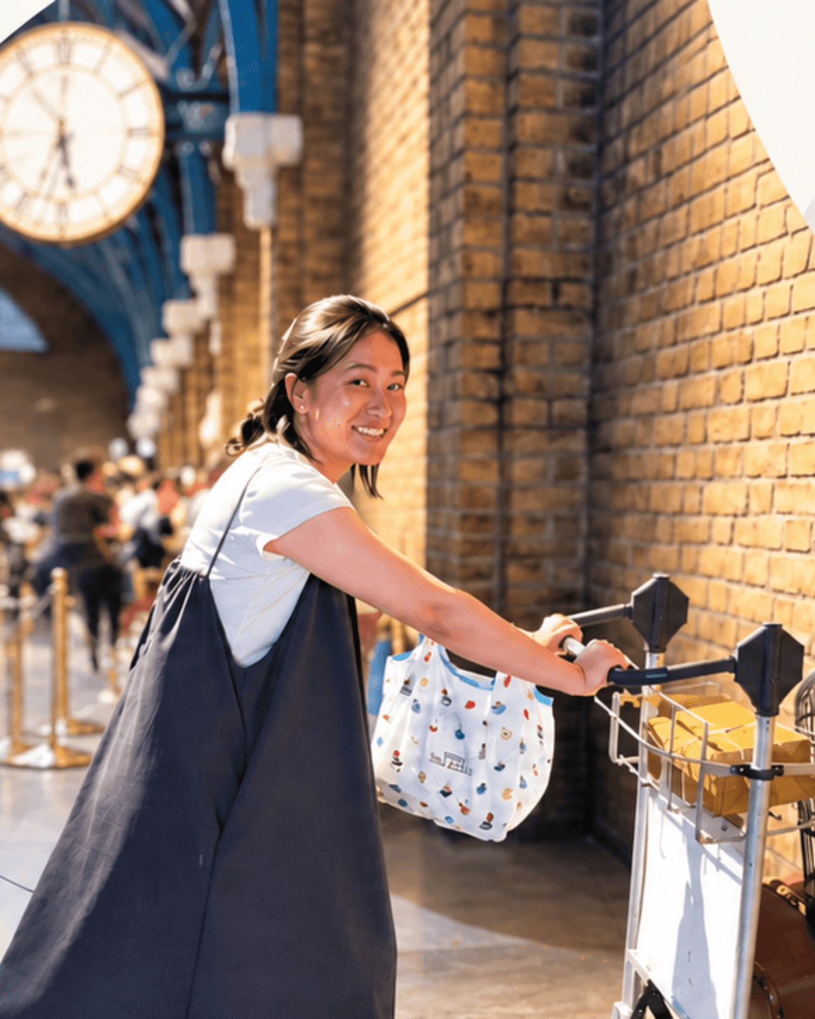 Mizuki smiling while pushing a luggage trolley in a sunlit station
